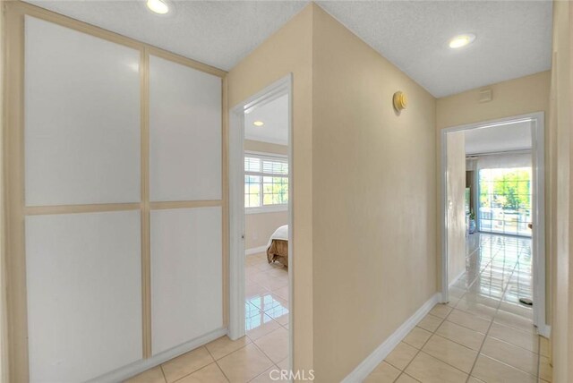 corridor with light tile patterned floors, baseboards, and recessed lighting