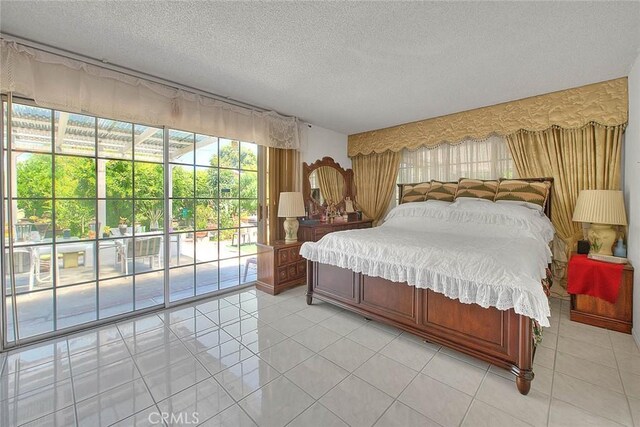 bedroom featuring access to exterior, a textured ceiling, and light tile patterned flooring