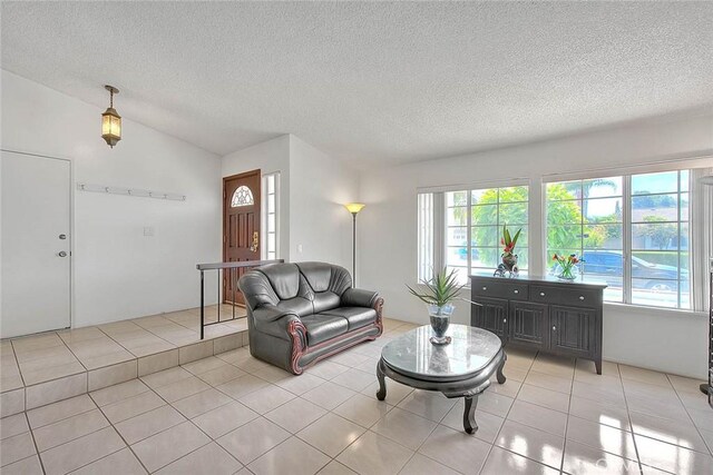 living area featuring a textured ceiling, vaulted ceiling, and light tile patterned floors