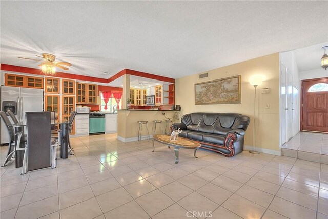living room with light tile patterned floors, ceiling fan, and baseboards