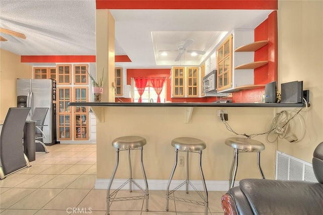 kitchen with appliances with stainless steel finishes, open shelves, dark countertops, a peninsula, and glass insert cabinets