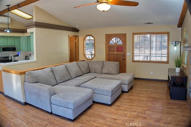 living room featuring light wood-style floors, lofted ceiling, ceiling fan, and visible vents