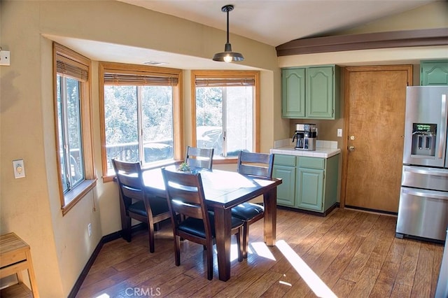 dining space featuring hardwood / wood-style floors, baseboards, and vaulted ceiling