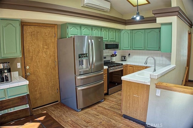 kitchen featuring green cabinets, light wood-style flooring, appliances with stainless steel finishes, tile countertops, and a sink