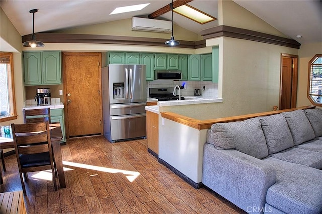 kitchen with vaulted ceiling, a sink, green cabinets, a wall unit AC, and appliances with stainless steel finishes