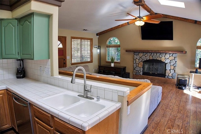 kitchen featuring ceiling fan, a sink, open floor plan, dark wood-style floors, and lofted ceiling with skylight