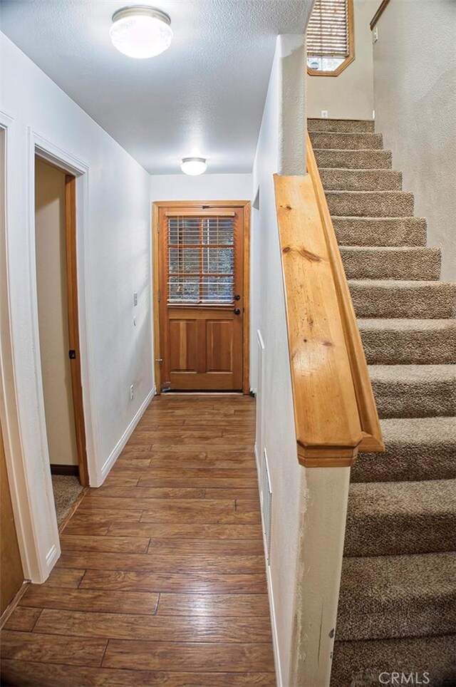 entryway with a textured ceiling, dark wood-style floors, baseboards, and stairway
