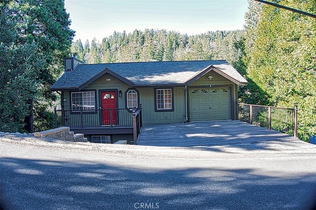 view of front of home featuring an attached garage, a chimney, driveway, covered porch, and a shingled roof