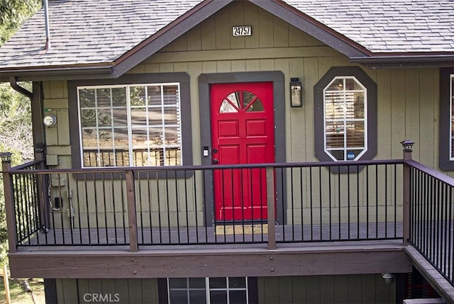 entrance to property featuring roof with shingles