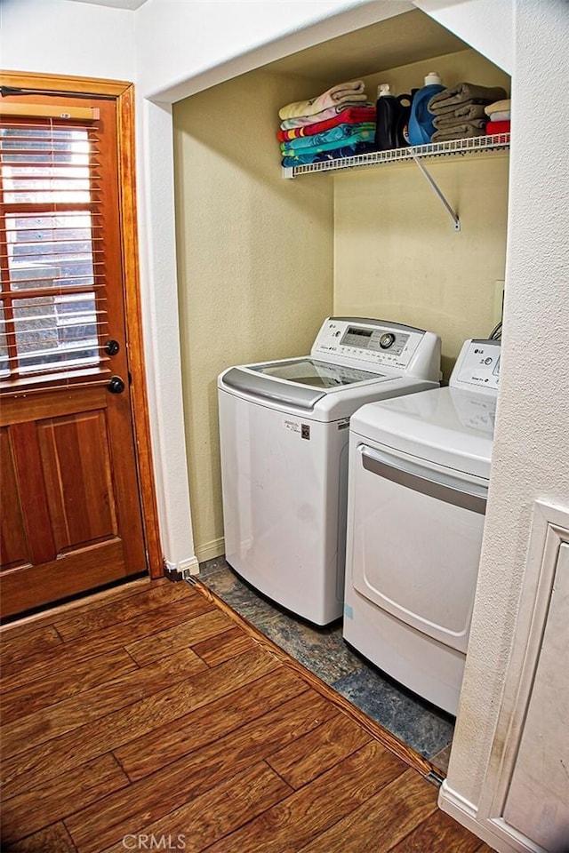 laundry area featuring baseboards, wood finished floors, washing machine and clothes dryer, and laundry area