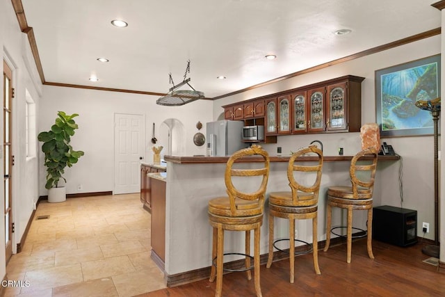 12617 Koenigstein Rd, Santa Paula, CA 93060 - kitchen featuring a kitchen bar, crown molding, a peninsula, appliances with stainless steel finishes, and glass insert cabinets