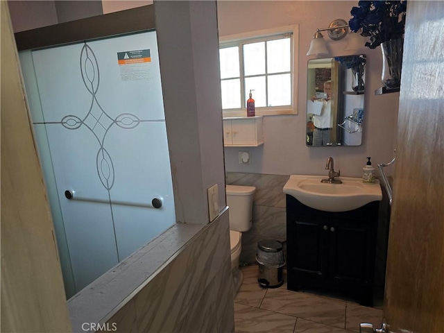 bathroom with tile walls, toilet, and vanity