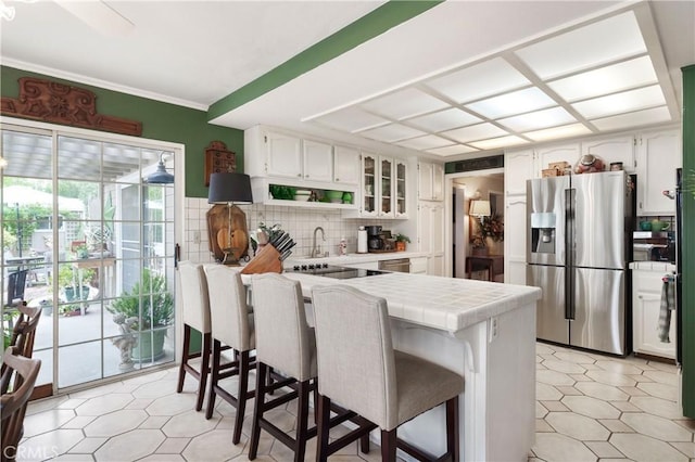 31065 Avenida Del Reposo, Temecula, CA 92591 - kitchen with a breakfast bar area, stainless steel refrigerator with ice dispenser, tile countertops, white cabinetry, and tasteful backsplash