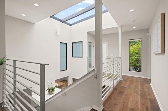 corridor featuring baseboards, recessed lighting, an upstairs landing, a skylight, and wood finished floors
