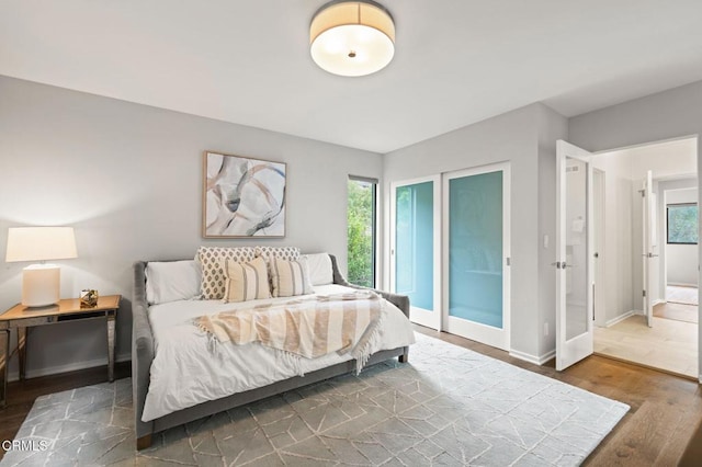 bedroom featuring baseboards, multiple windows, and wood finished floors