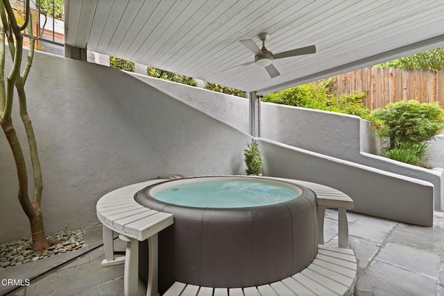 view of patio / terrace featuring fence, an outdoor hot tub, and a ceiling fan