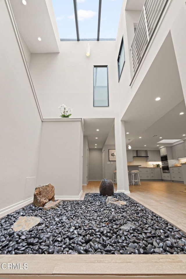 foyer with a towering ceiling, baseboards, and wood finished floors