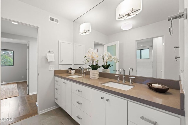 full bath with double vanity, visible vents, baseboards, and a sink