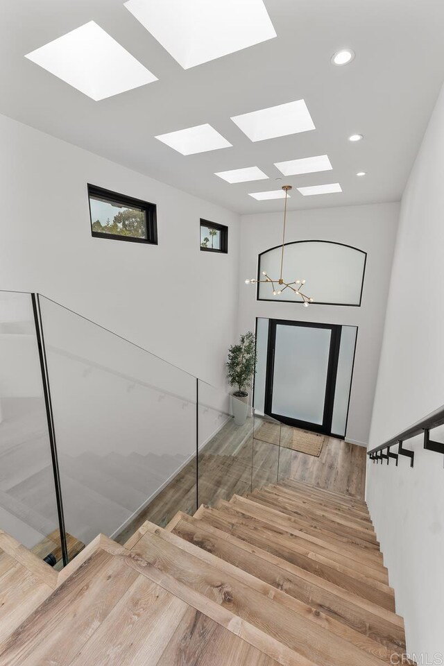 stairway featuring a skylight, wood finished floors, a chandelier, and recessed lighting