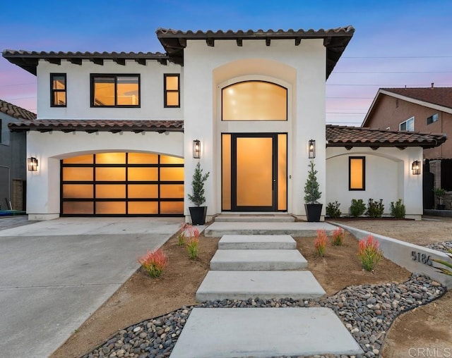view of front of home featuring a tiled roof, concrete driveway, stucco siding, and an attached garage