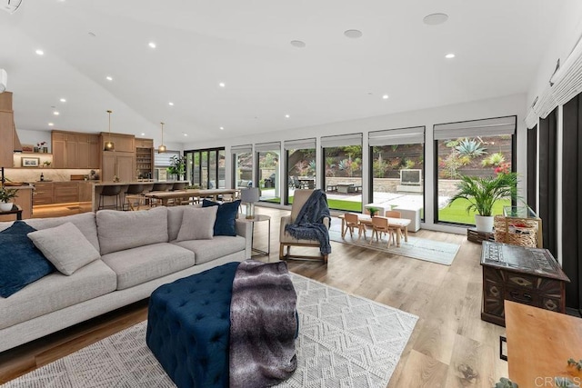 living area with lofted ceiling, light wood-style flooring, and recessed lighting