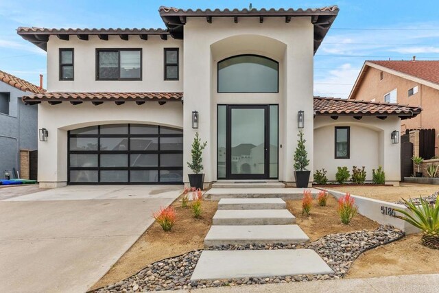 mediterranean / spanish house featuring stucco siding, a garage, and concrete driveway
