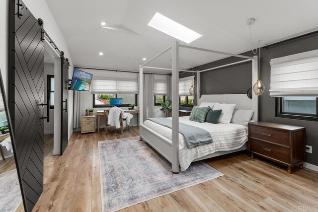 5186 Maynard St, San Diego, CA 92122 - bedroom featuring a barn door, light wood-style floors, a skylight, and recessed lighting