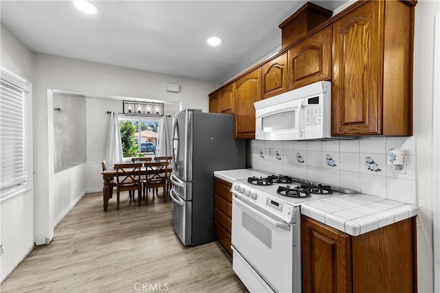 11525 Corby Ave, Norwalk, CA 90650 - kitchen with white appliances, light wood-style flooring, backsplash, brown cabinetry, and recessed lighting