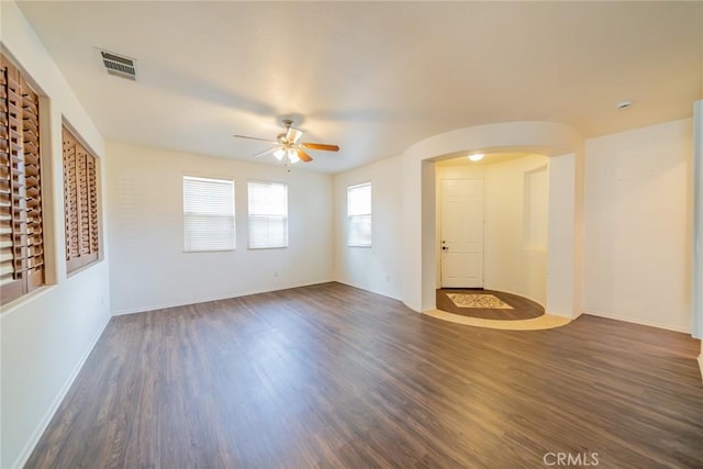 unfurnished living room featuring visible vents, wood finished floors, arched walkways, and a ceiling fan