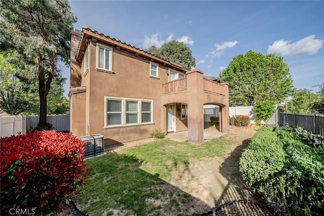 back of house with central air condition unit, stucco siding, a fenced backyard, a balcony, and a patio area