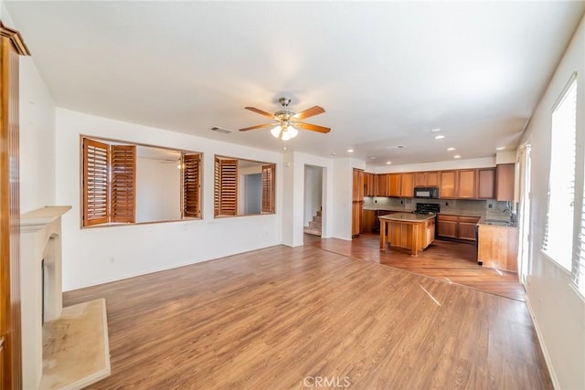kitchen featuring tasteful backsplash, light wood-style floors, visible vents, black microwave, and brown cabinetry