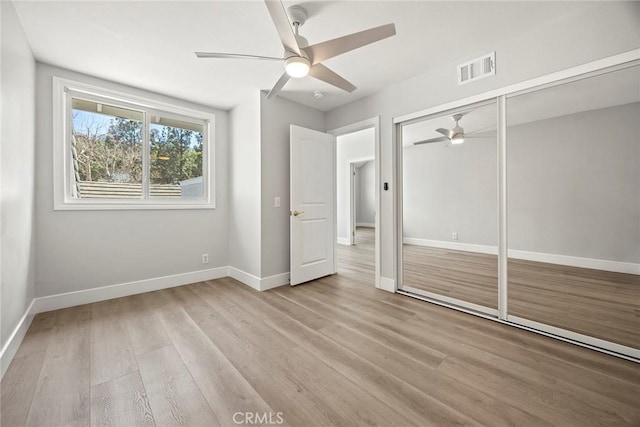 unfurnished bedroom featuring a closet, light wood-style flooring, visible vents, and baseboards