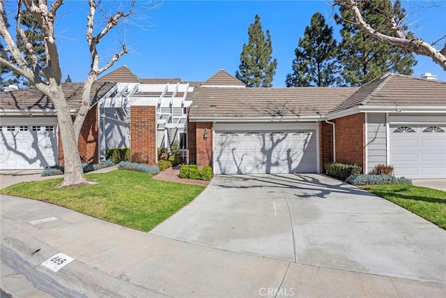 view of front of property with a tile roof, brick siding, driveway, and a front lawn