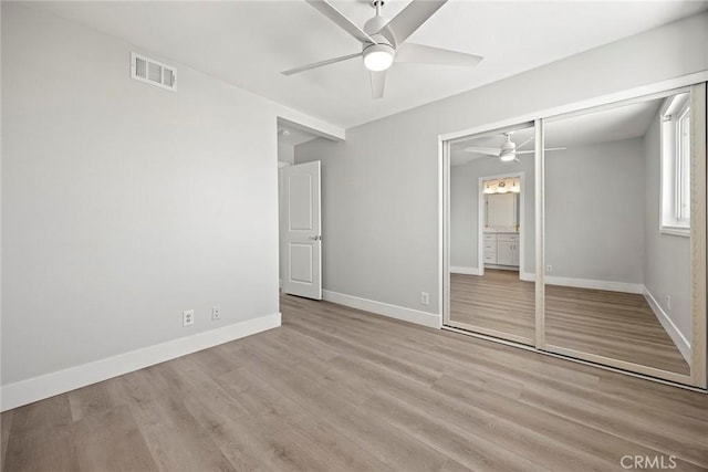 unfurnished bedroom featuring wood finished floors, a closet, ceiling fan, baseboards, and visible vents