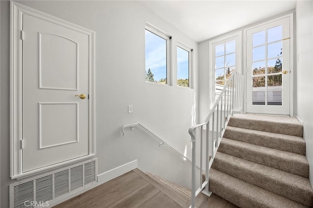 staircase with baseboards, wood finished floors, and visible vents