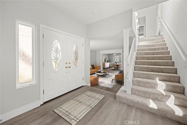 entrance foyer with baseboards, wood finished floors, and stairs