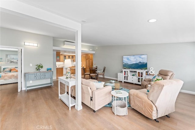 living room featuring wood finished floors, a wall mounted AC, baseboards, and recessed lighting