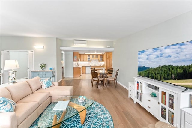 living room featuring light wood finished floors, a wall mounted air conditioner, and baseboards