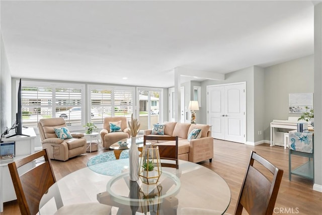dining space with healthy amount of natural light, light wood-style flooring, and baseboards