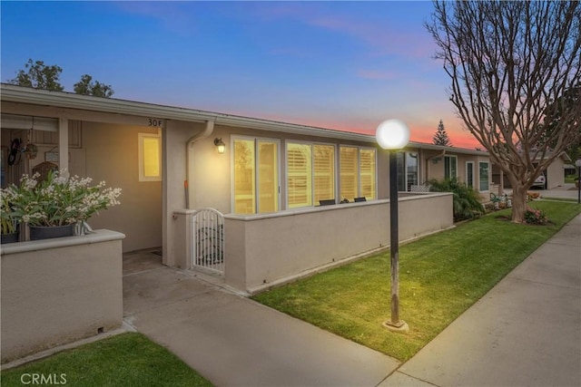 view of front of property with stucco siding, a front lawn, and a gate