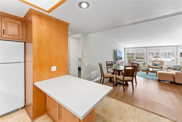 kitchen featuring freestanding refrigerator, a peninsula, light countertops, open floor plan, and recessed lighting