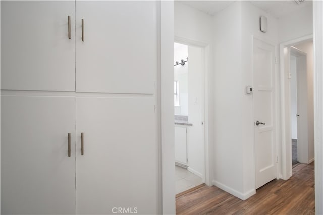 corridor featuring baseboards and wood finished floors