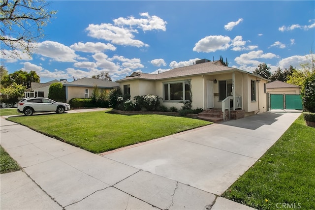ranch-style house featuring an outbuilding, concrete driveway, stucco siding, a front yard, and a garage