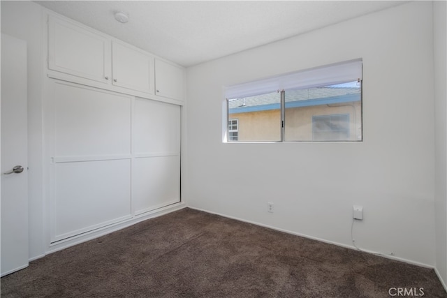 unfurnished bedroom with a closet and dark colored carpet