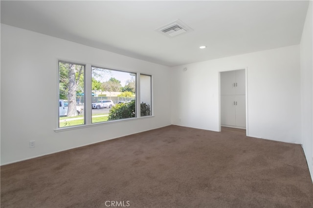 carpeted empty room featuring visible vents and recessed lighting