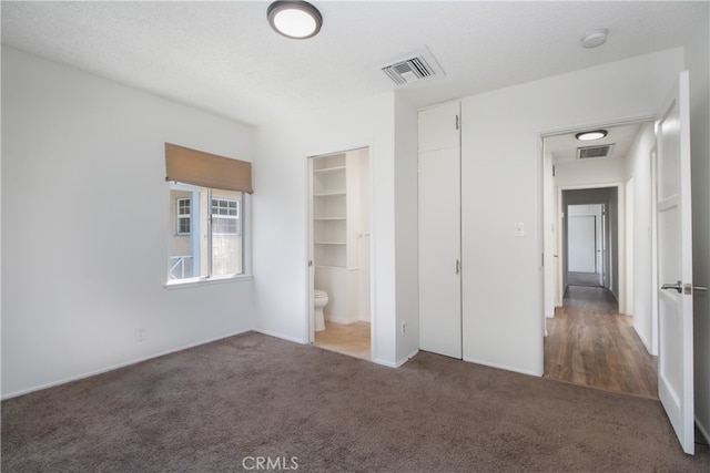 unfurnished bedroom featuring visible vents, carpet, and a textured ceiling