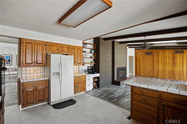 kitchen with open shelves, brown cabinetry, tile countertops, white fridge with ice dispenser, and carpet floors