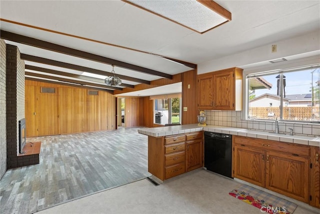kitchen featuring a sink, brown cabinetry, open floor plan, dishwasher, and a wealth of natural light