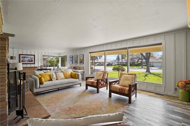 living area with a decorative wall, wood finished floors, and visible vents