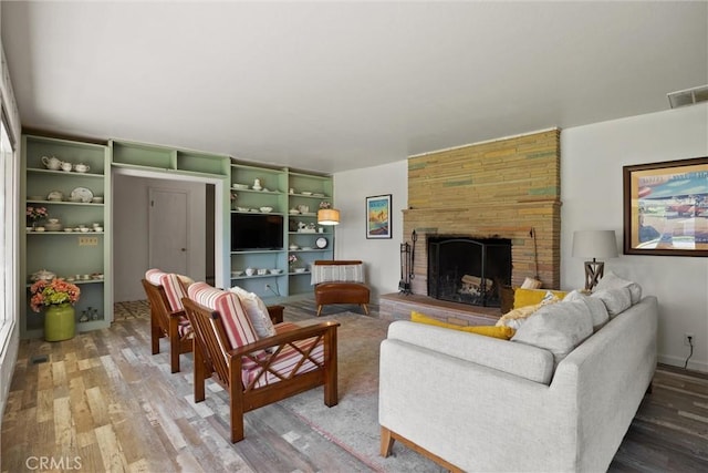 living area featuring a fireplace, light wood-style flooring, and visible vents